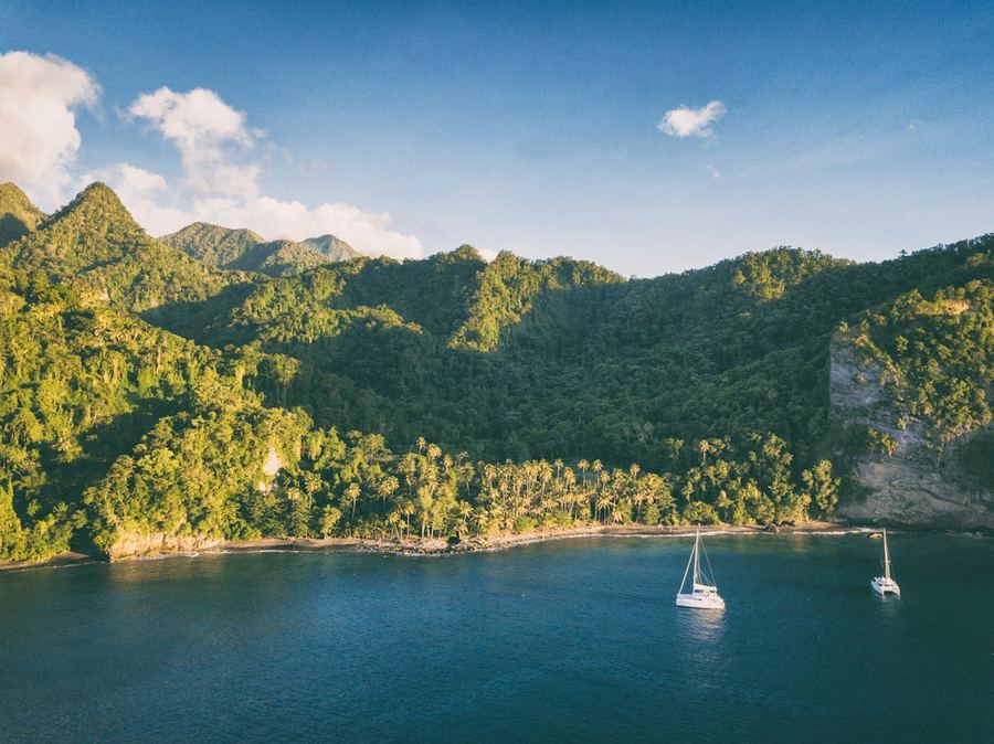 Green forested hills above a calm bay with sailboats at anchor